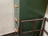 une pile de tiroirs verts dans une pièce, à côté d'une échelle
