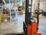 a forklift in a large warehouse with lots of work on it