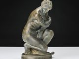 une statue représentant un homme assis sur un socle, les mains posées sur les genoux