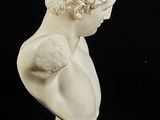 white marble bust of a boy with curly hair on a pedestal