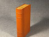 a small orange book sitting on a gray surface