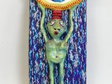 sculpture of a green alien holding a blue eye above its head