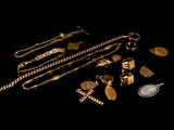 gold jewelry on a black background with a coin in the foreground