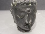 une petite statue représentant une tête, posée sur une table