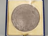 an image of a silver medal in a blue box with a ribbon around it