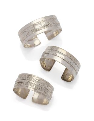 un lot de trois bracelets manchette en argent sur fond blanc