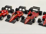 six voitures de course rouges alignées sur une surface blanche