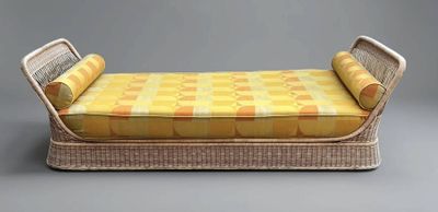 un lit de jour en osier recouvert d'un drap à carreaux jaunes et blancs