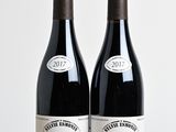 two bottles of wine sitting on top of a wooden table next to each other