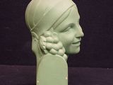 a green sculpture of a woman with a flower in her hair