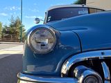 a blue classic car parked in front of a building