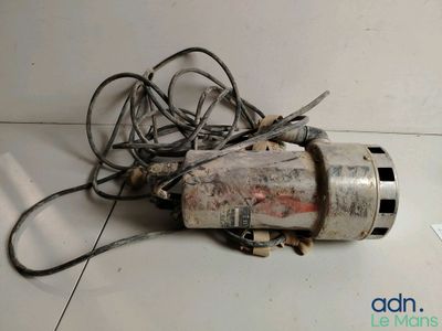 une petite perceuse électrique posée par terre à côté d'un enchevêtrement de fils