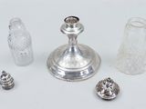a silver candle holder, salt shaker, and other items on a white surface