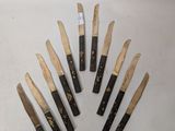 six knives are lined up in a circle on a white surface
