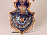 a blue and gold vase on a stand on a white surface
