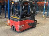 a red forklift in a warehouse with lots of pallets