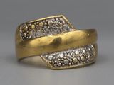 une image représentant une bague en or sertie de diamants posée sur une surface grise