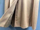 le dos d'un manteau beige accroché à un mur bleu