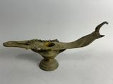 une vieille lampe à huile en laiton surmontée d'un oiseau
