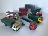 Plusieurs camions miniatures sont alignés sur une surface blanche