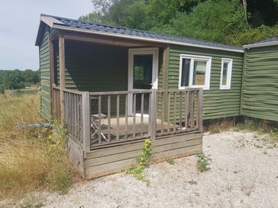 une petite maison verte avec un porche et un balcon