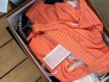 an orange and white striped shirt in a box on a wooden table