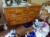 une commode sur laquelle se trouve un panier rempli de poupées