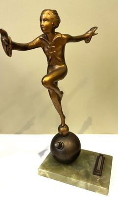 bronze statue of a boy balancing on a ball on a marble base