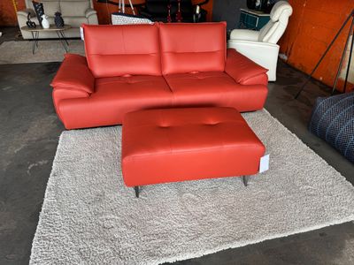 une photo d'un salon avec un canapé rouge et un pouf