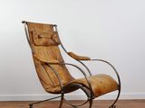 un vieux fauteuil à bascule dans une pièce avec un parquet et un mur blanc