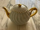 a white and gold teapot sitting on a marble table