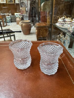 two glass vases sitting on a table in front of a glass case