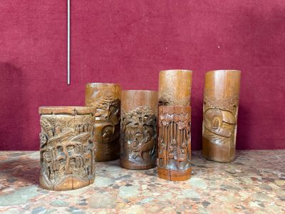 quatre vases en bois ornés de sculptures, posés sur une table