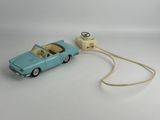 a toy car connected to a charger on a white surface