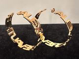 a close up of a pair of gold hoop earrings on a black surface