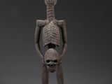 une figurine en bois représentant un squelette tenant un crâne entre ses mains