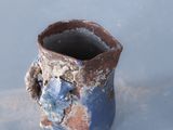 a blue and brown vase sitting on a white surface