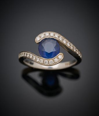 un gros plan d'une bague en saphir et diamants posée sur une surface noire