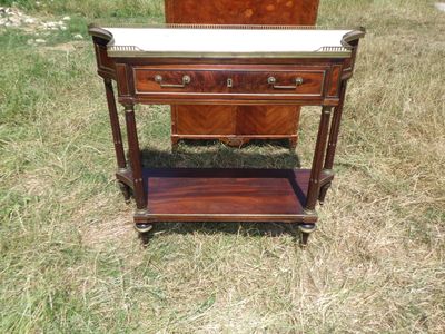 une petite table en bois avec un plateau en marbre posée sur l'herbe