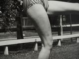 black and white photograph of a woman in a bathing suit holding a baseball bat