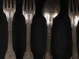 four forks and spoons are lined up against a black background