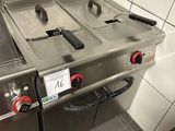 deux cuisinières en acier inoxydable avec des boutons rouges dans une cuisine