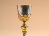 an antique silver and gold goblet on a beige background