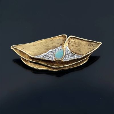 a close up of a gold plate with a turquoise stone in it