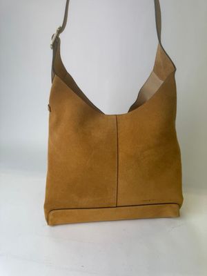 une photo d'un sac à main marron posé sur une table blanche