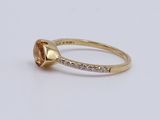 a close up of a yellow gold ring with an oval stone surrounded by small diamonds