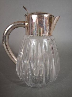 a glass pitcher with a silver lid on a table
