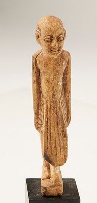 Une statuette en os, représentant un prêtre égyptien vêtu d'…