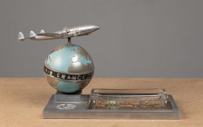 une maquette d'avion argentée et bleue posée sur un globe terrestre