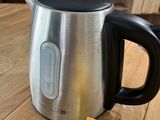a silver kettle sitting on a wooden table next to a packet of lemonade